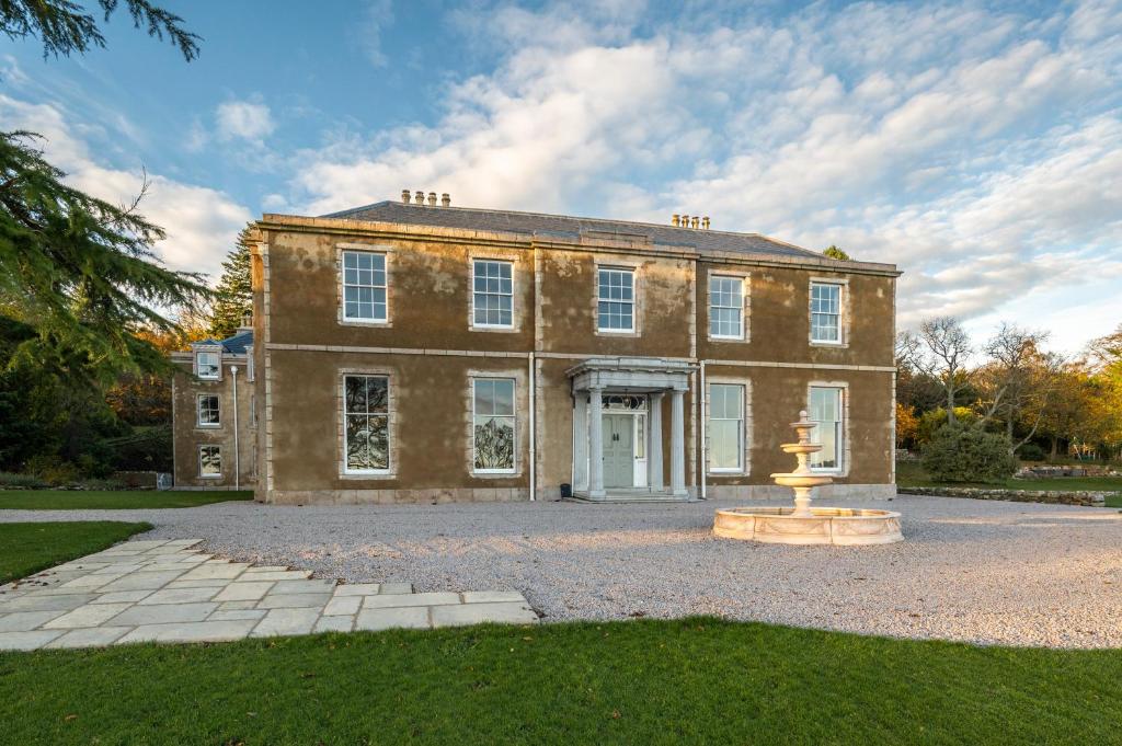 a large brick house with a fountain in front of it at Manar House Ground Floor Luxury Apartment in Inverurie