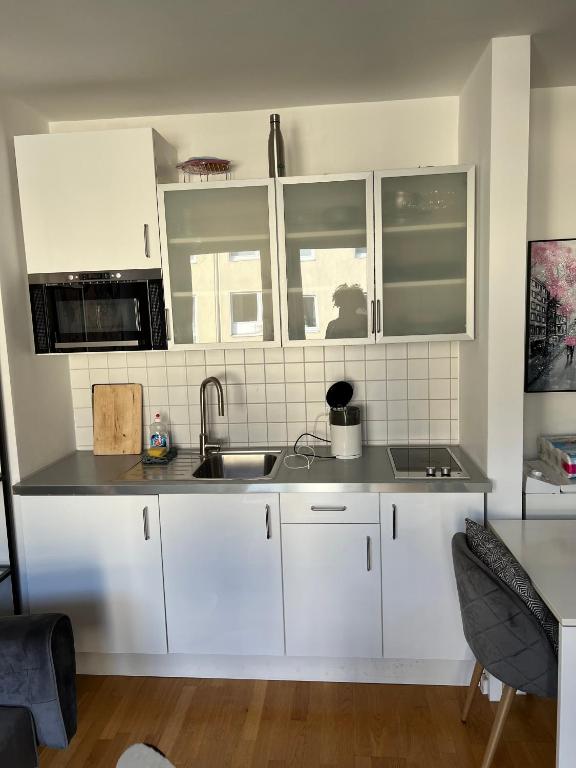 ケルンにあるKölner City Stillvolle Apartmentの白いキャビネットとシンク付きのキッチン