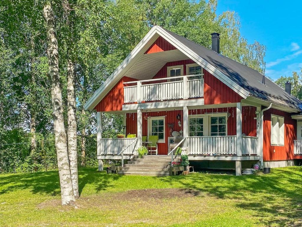 a red house with a balcony and a tree at Holiday Home Casa rantapirtti by Interhome in Jyväskylä