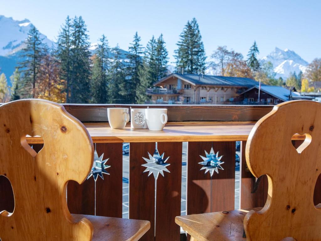 2 sillas de madera sentadas sobre una mesa en un balcón en Apartment Brotzet Ensoleillé by Interhome, en Gryon