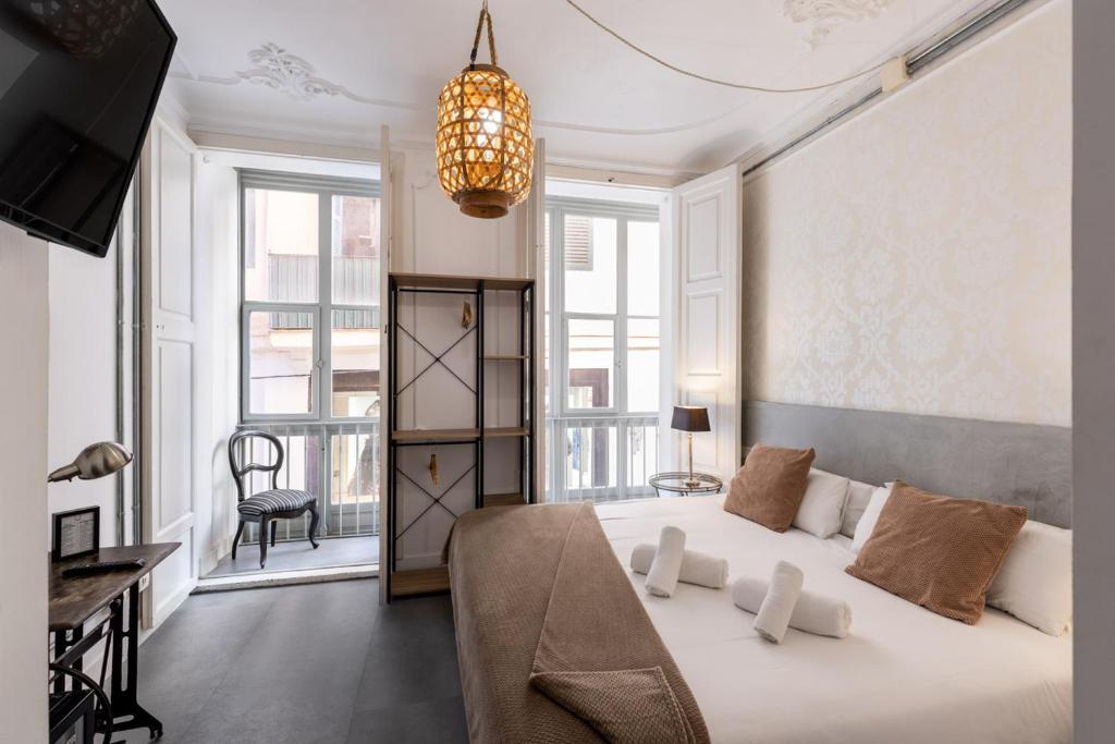 Un dormitorio con una gran cama blanca y una lámpara de araña. en Antiguo Brondo Selfcheck-in Smart Rooms, en Palma de Mallorca