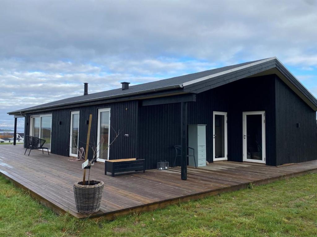 a black house with a wooden deck in a field at Holiday Home Ferdine - 1-5km from the sea by Interhome in Knebel