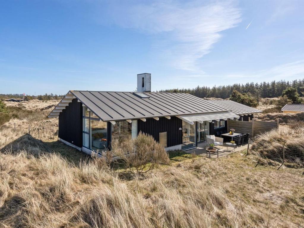 Une petite maison noire au milieu d'un champ dans l'établissement Holiday Home Annrike - 400m from the sea in NW Jutland by Interhome, à Saltum