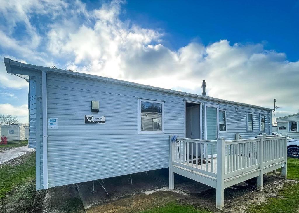 a blue tiny house with a white porch at Spacious Caravan On The Suffolk Coast With Outside Decking Too Ref 20044bs in Hopton on Sea