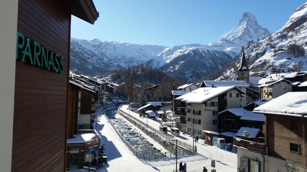 a view of a town with snow covered mountains at Hotel Parnass in Zermatt