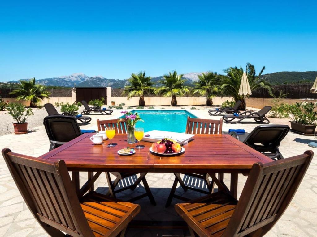 mesa de comedor de madera con sillas y piscina en Holiday Home Can Melis by Interhome, en Campanet