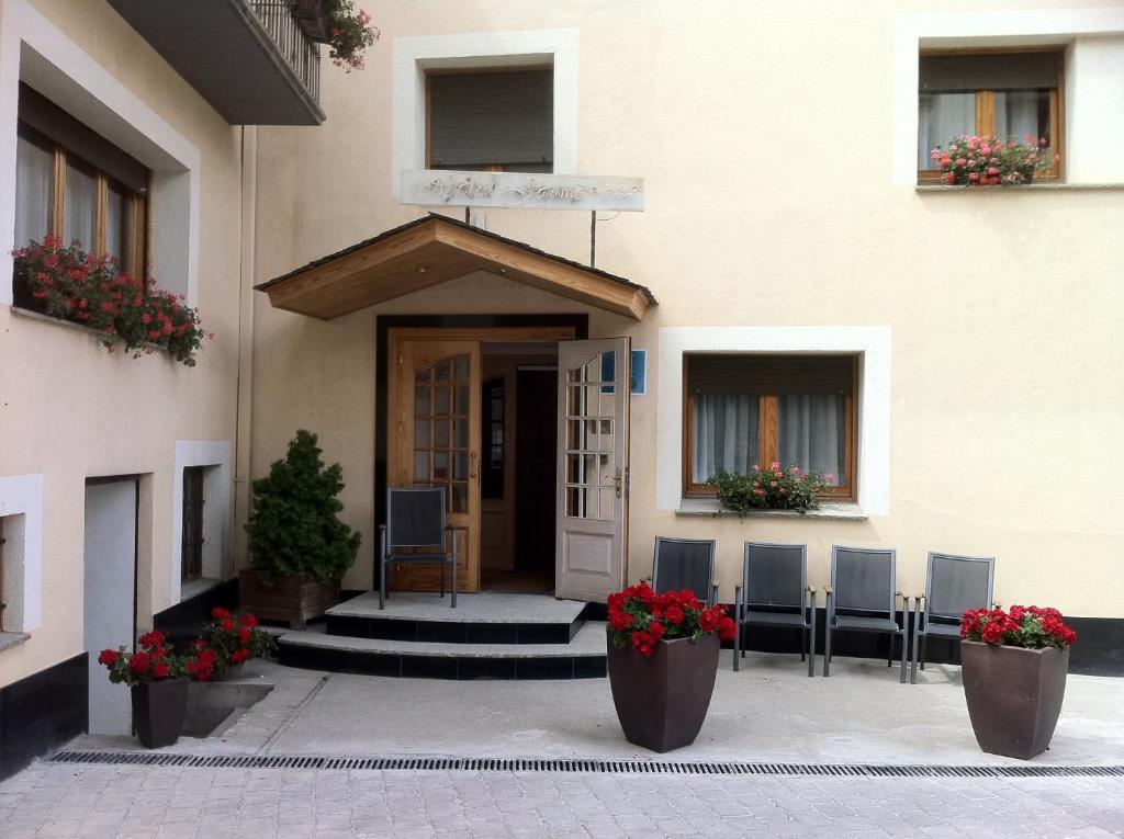 een voordeur van een gebouw met stoelen en bloemen bij Hotel Jaume in Alp