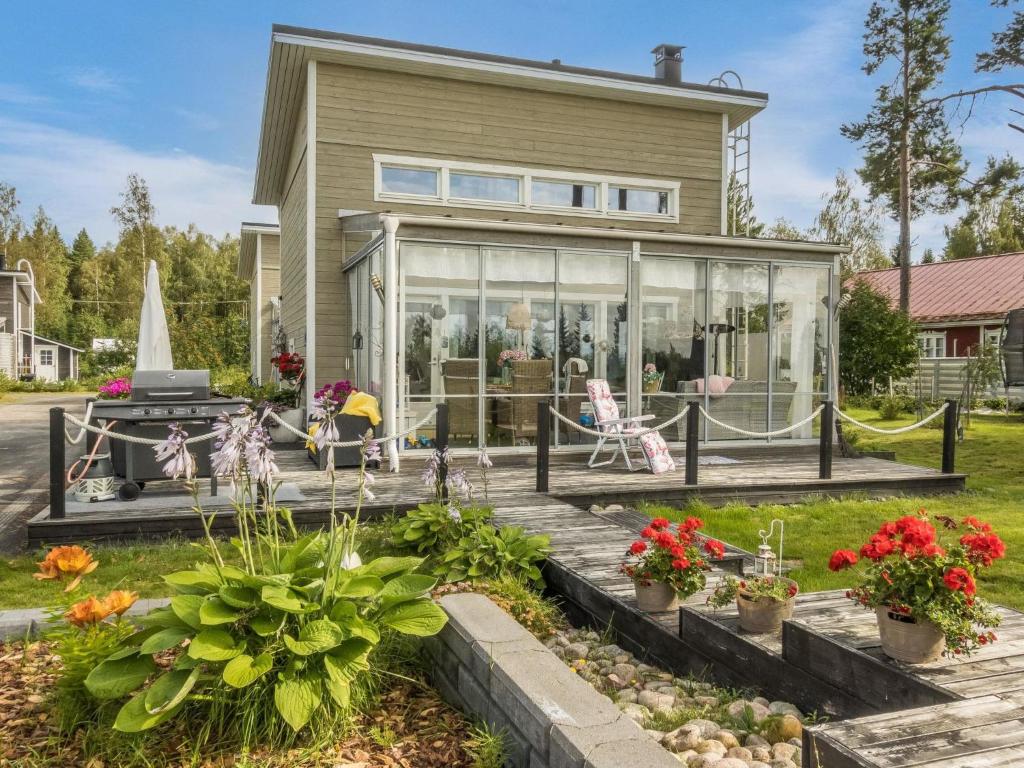 a house with glass doors and flowers in the yard at Holiday Home Peuhu a4 by Interhome in Oulunsalo