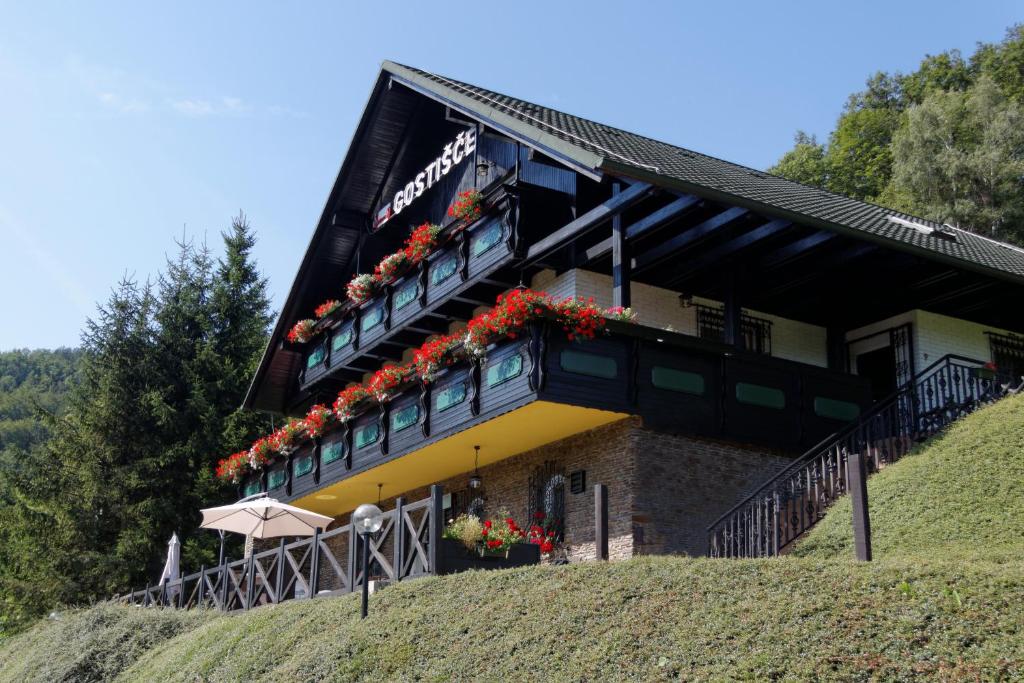 een gebouw op een heuvel met bloemen op het balkon bij Pod Orehi Guest House in Loče pri Poljčanah