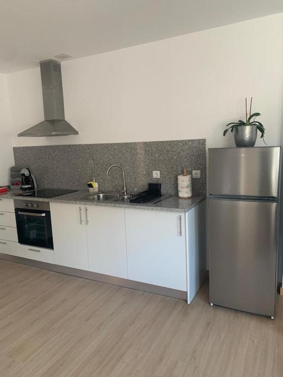 a kitchen with white cabinets and a stainless steel refrigerator at Pôr do Sol in Bragança