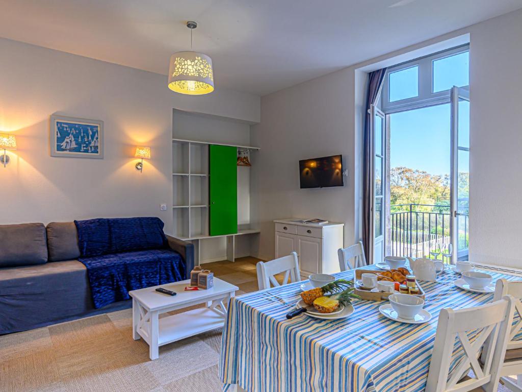 a living room with a table and a blue couch at Apartment Le Château de Kergonano-8 by Interhome in Baden