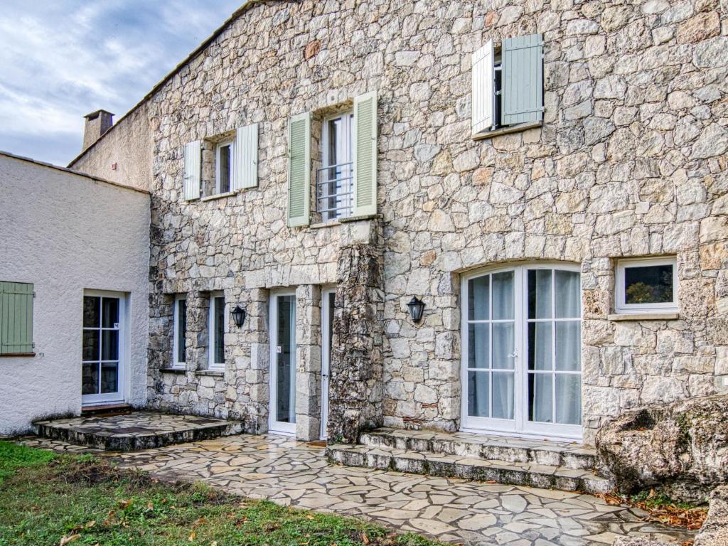 un edificio de piedra con puertas y ventanas blancas en Holiday Home Les Grenaches by Interhome, en Draguignan