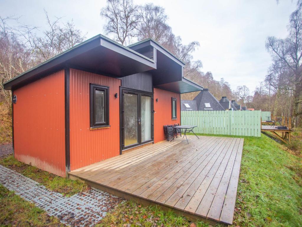 a small house with a wooden deck in a yard at Chalet Dougie's by Interhome in Drumnadrochit