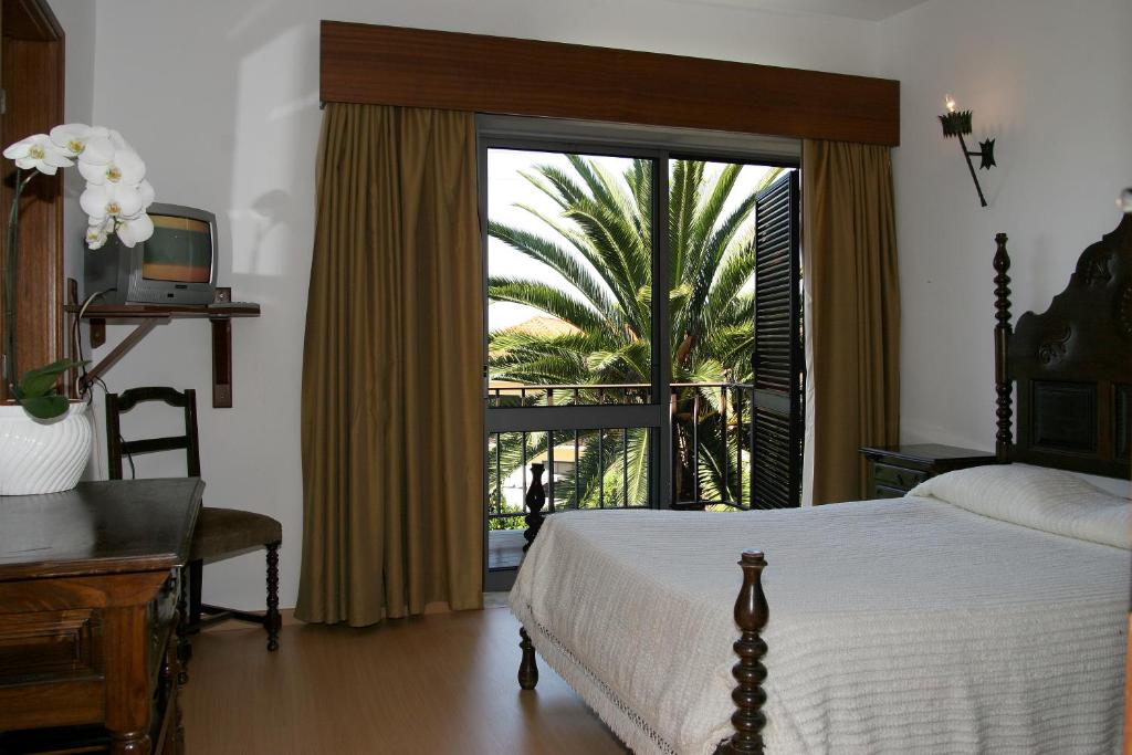 a bedroom with a bed and a sliding glass door at Arcada Hotel in Tocha