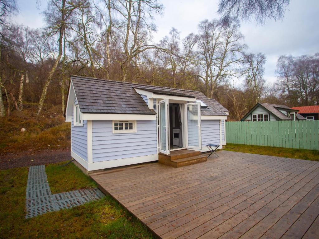 a small white shed with a wooden deck at Chalet Affric 3 by Interhome in Drumnadrochit