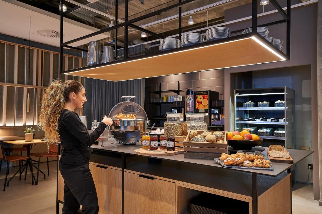 a woman standing in front of a counter with food at Zleep Hotel Lausanne-Chavannes NEW OPENING in Lausanne