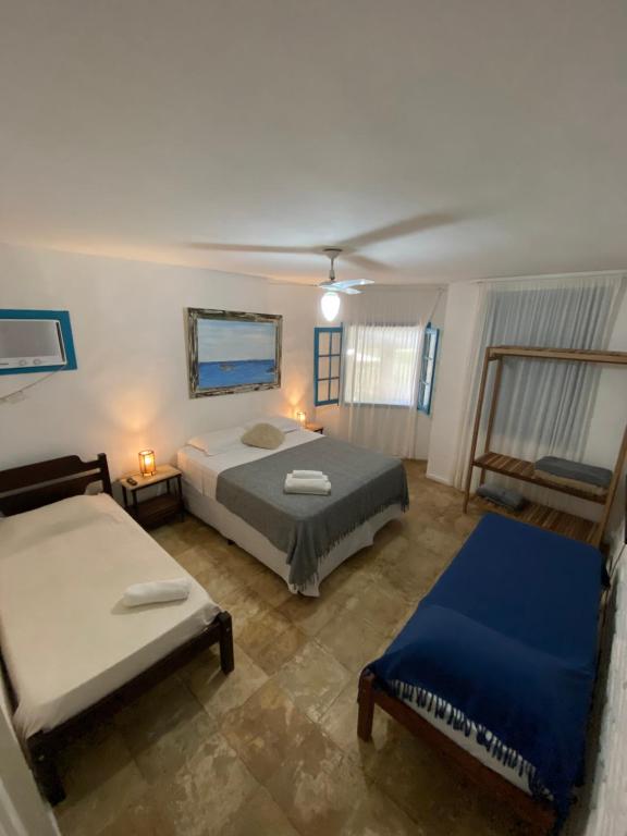 a bedroom with two beds and a chair in it at Peixe Crew Manguinhos in Búzios