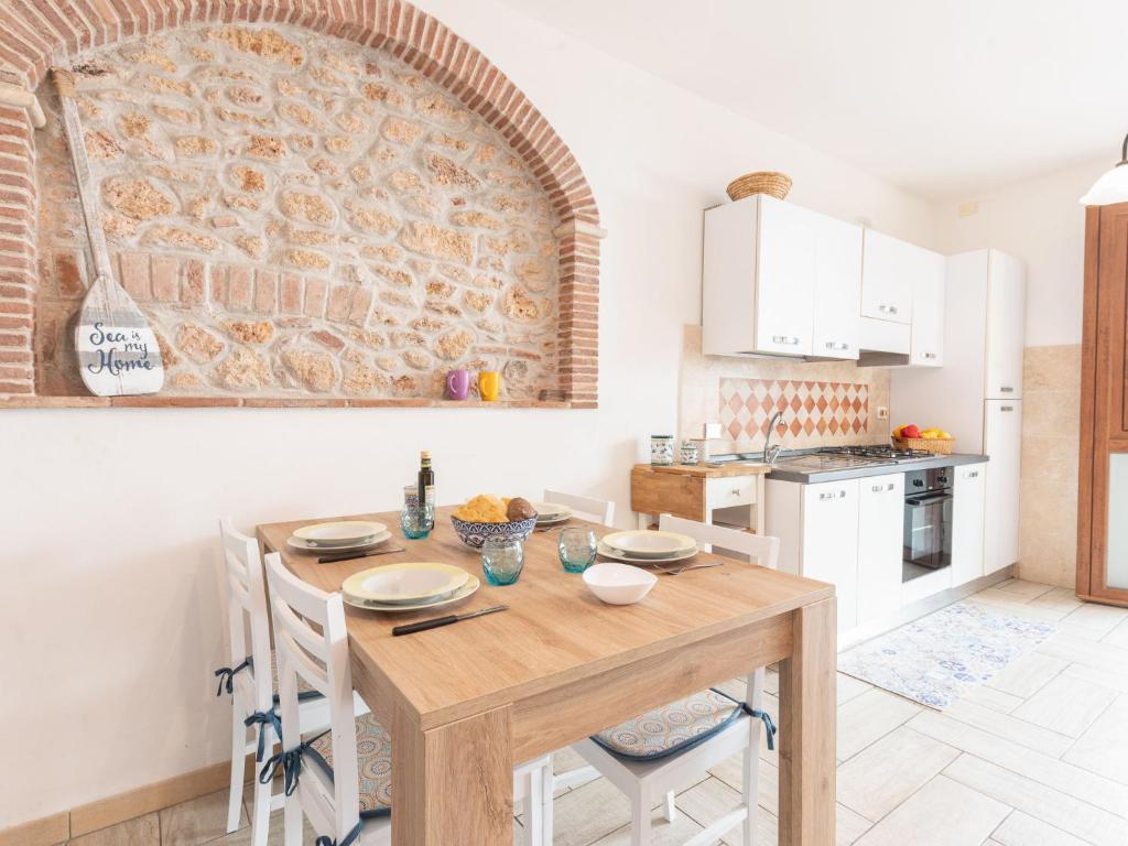 uma cozinha com uma mesa de madeira e armários brancos em Apartment La Casetta dei Pescatori by Interhome em Follonica