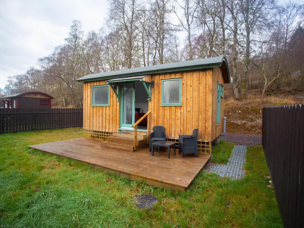 Cabaña de madera con 2 sillas en una terraza en Chalet Plodda 4 by Interhome en Drumnadrochit