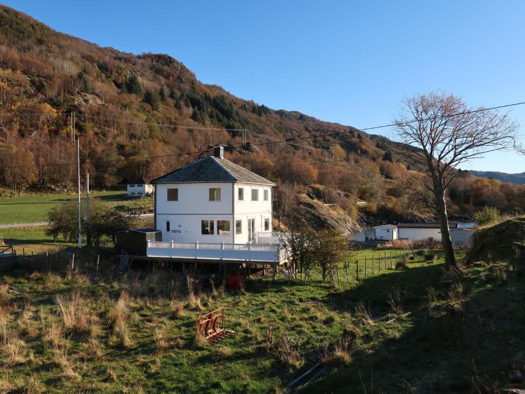 a white house in a field with a mountain at Holiday Home Sjøtun - FJS155 by Interhome in Hyllestad
