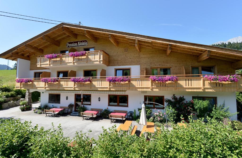 a building with a balcony and tables and chairs at Pension Aloisia in Scheffau am Wilden Kaiser