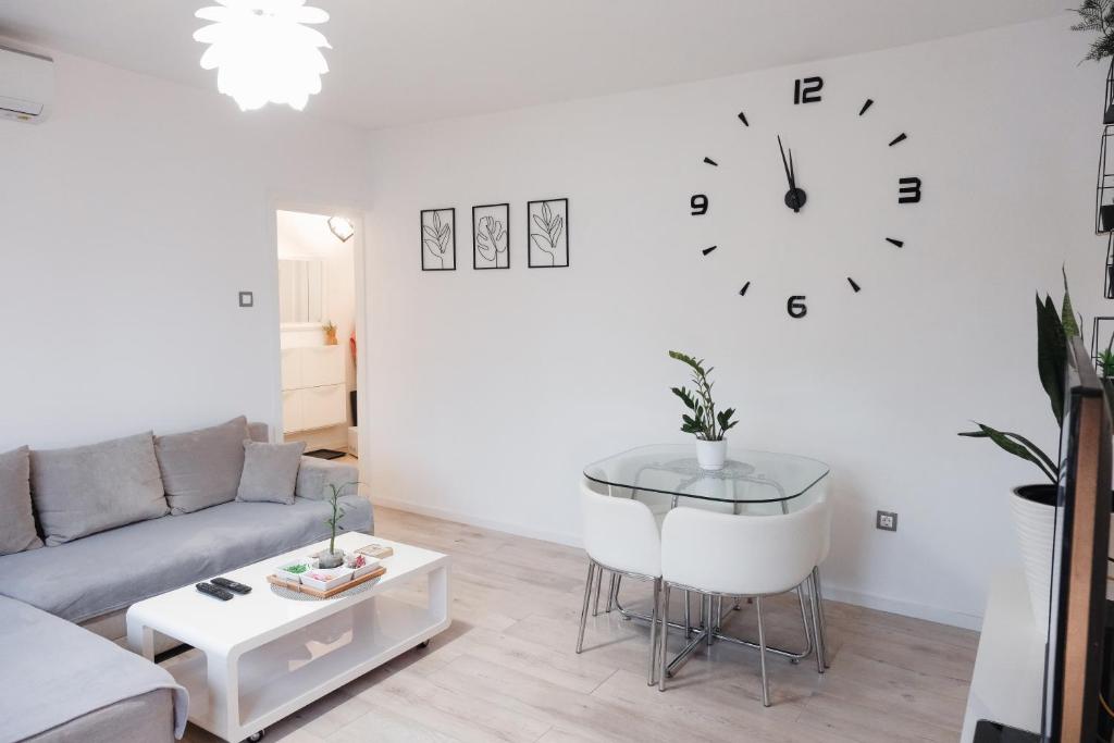 a living room with a couch and a clock on the wall at Apartman Franko - SELF CHECK IN in Osijek