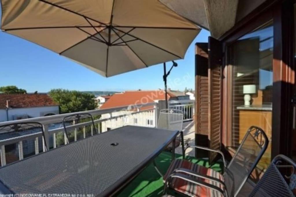 uma mesa e cadeiras numa varanda com um guarda-sol em 3 Bedroom Ana's Rest Apartment by the sea em Kaštela
