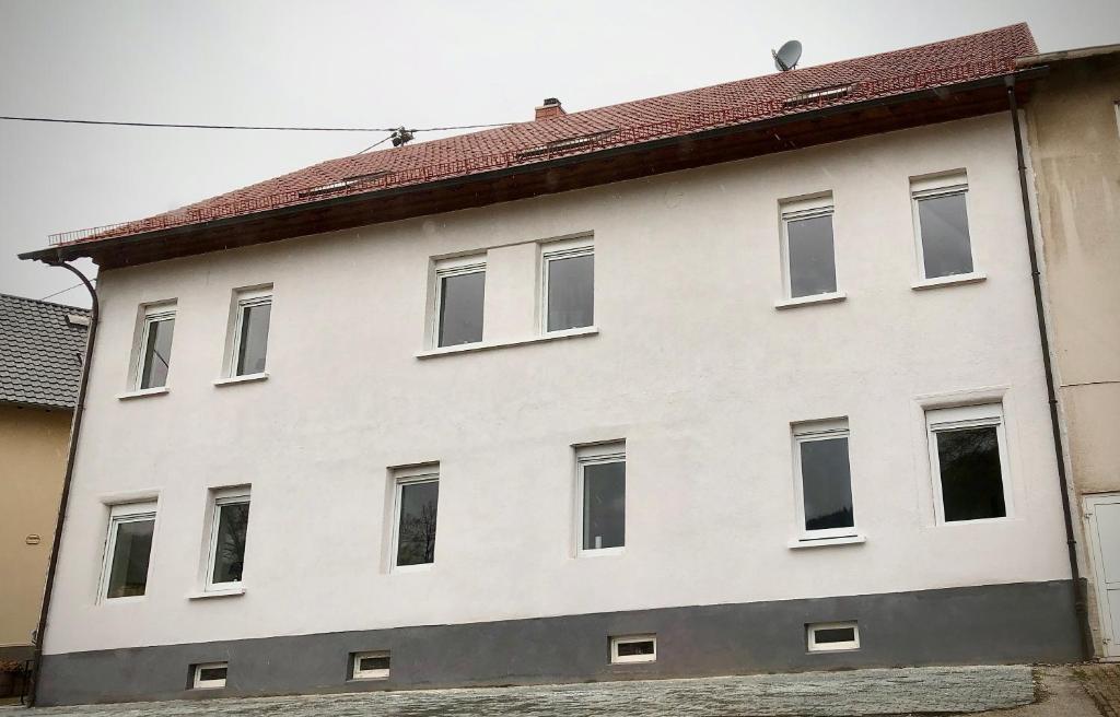 um edifício branco com um telhado vermelho em Schneiders Ferienwohnung 5 em Braunshausen