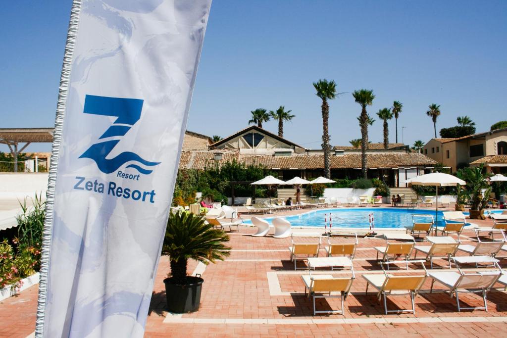 希克利的住宿－Zeta Resort Donnalucata，一个带椅子和游泳池的迷人度假胜地的标志