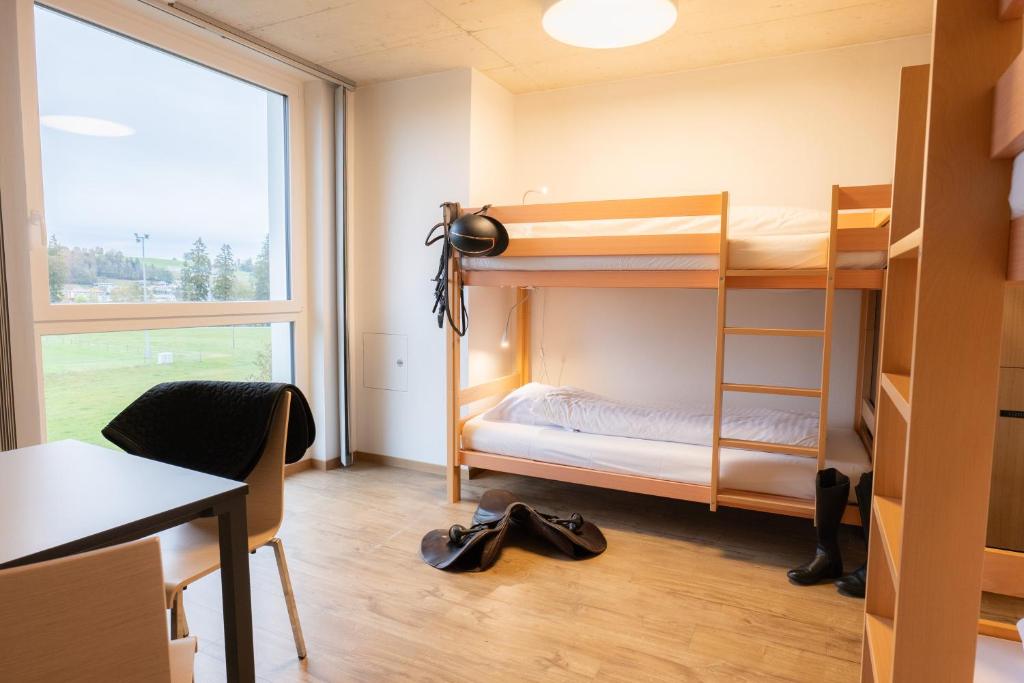 a dorm room with bunk beds and a desk at Auberge de Jeunesse Saignelégier in Saignelégier