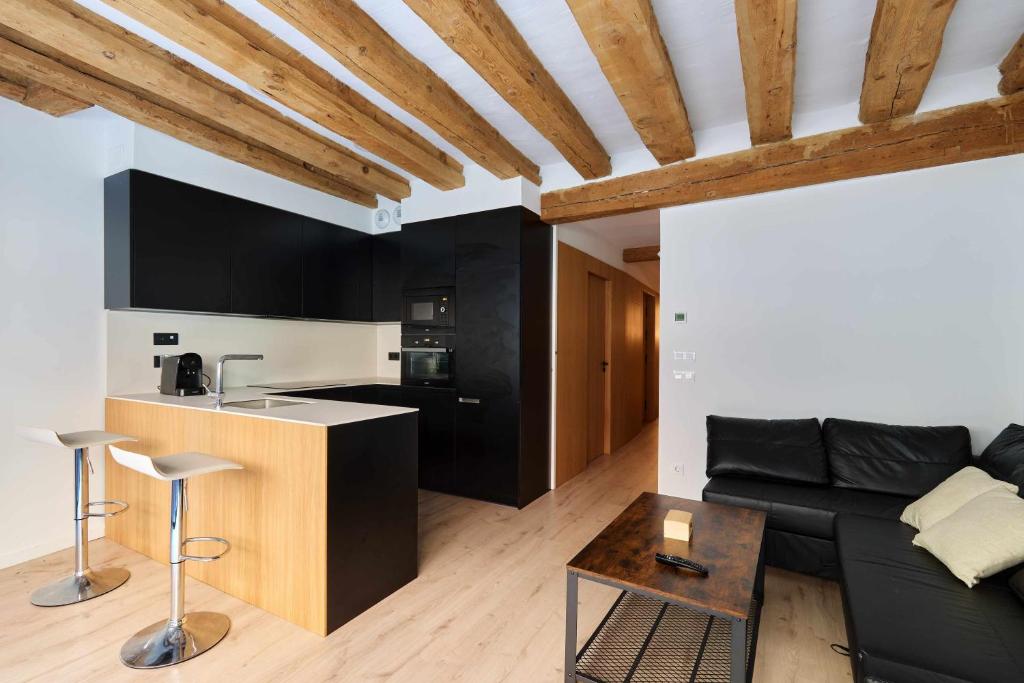 a living room with a black couch and a kitchen at Apartamento Chapitela Deluxe in Pamplona