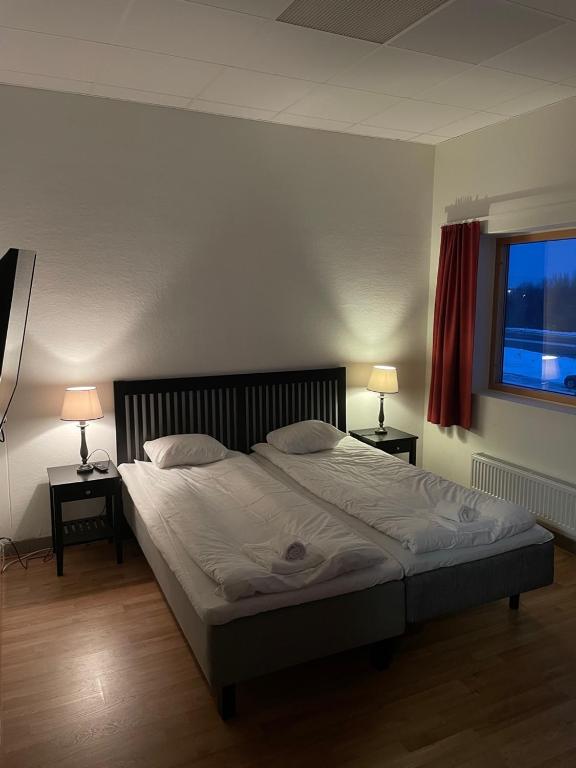 a bedroom with a large bed with two lamps on tables at Trestads Värdshus in Vänersborg