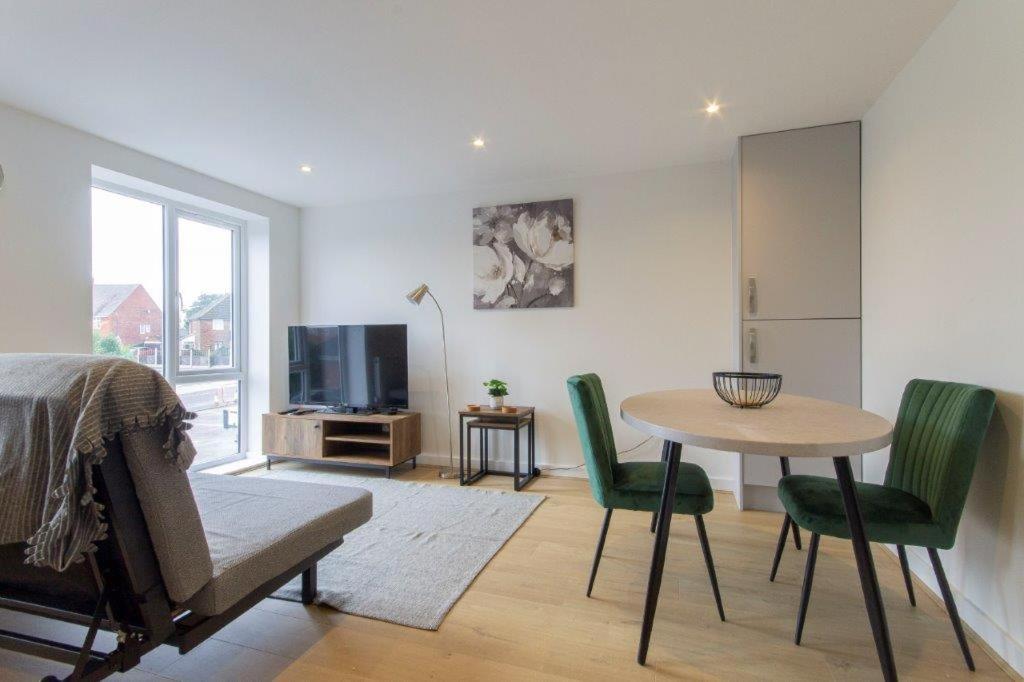 a living room with a table and green chairs at All Inn Apartments in Staveley