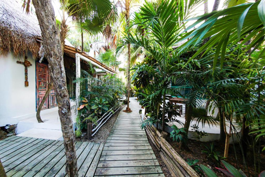 een houten loopbrug naar een huis met palmbomen bij Hotel Cormoran Tulum & Cenote in Tulum