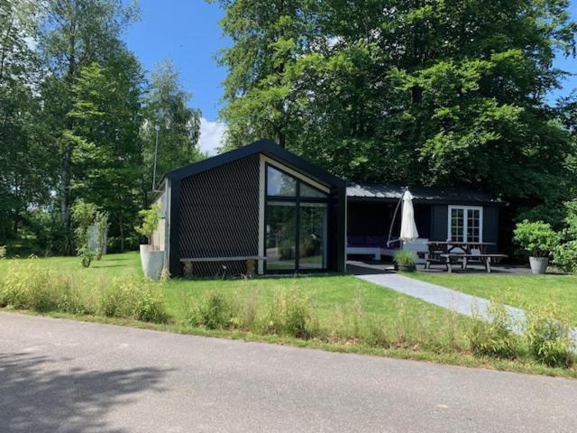 een zwart tiny house in het midden van een veld bij Luxe chalet in Oosterwolde in FRIESLAND, op rustig park met uitzicht op meer en strandje in Oosterwolde