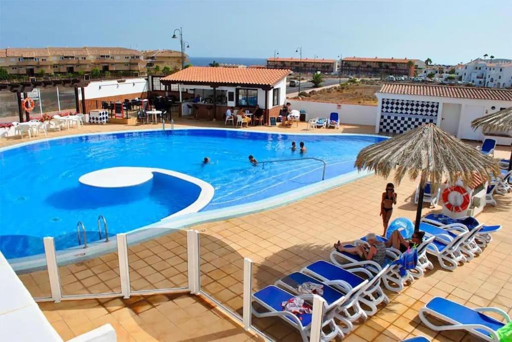 una gran piscina con sillas y gente en ella en Oasis Retreat 793 - Appartamento con piscina a Amarilla Golf, en San Miguel de Abona