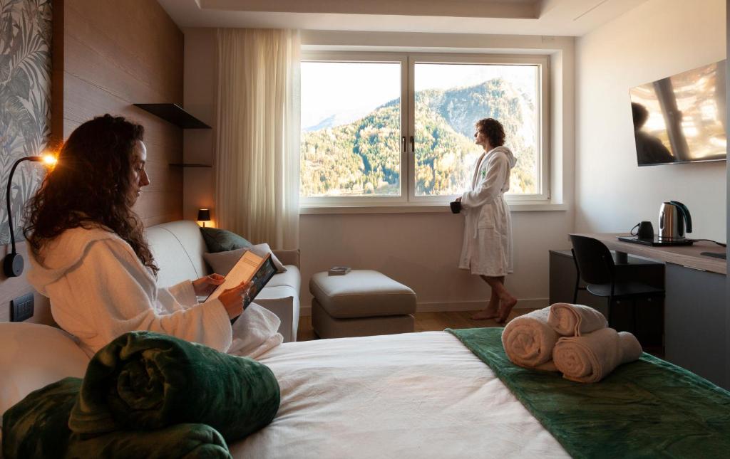 una mujer parada en una habitación de hotel mirando por la ventana en Il Quadrifoglio - alloggio turistico, en Valle di Cadore