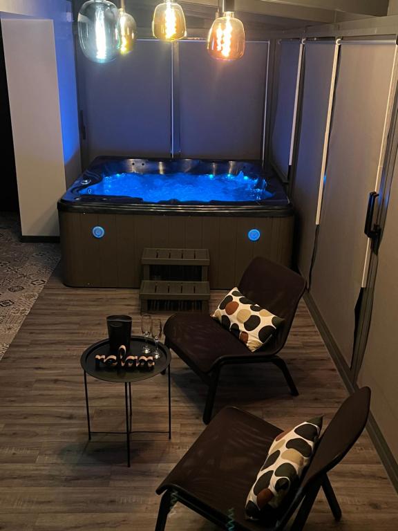 a hot tub in a room with a table and chairs at PAUSE NATURE SORBAIS gîte 2 personnes avec grand SPA privatif, STREAMING et arrivée autonome in Sorbais
