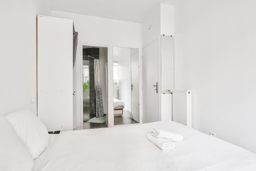 a white bedroom with a mirror and a white bed at Superbe T2 à proximité du parc Georges Brassens in Paris