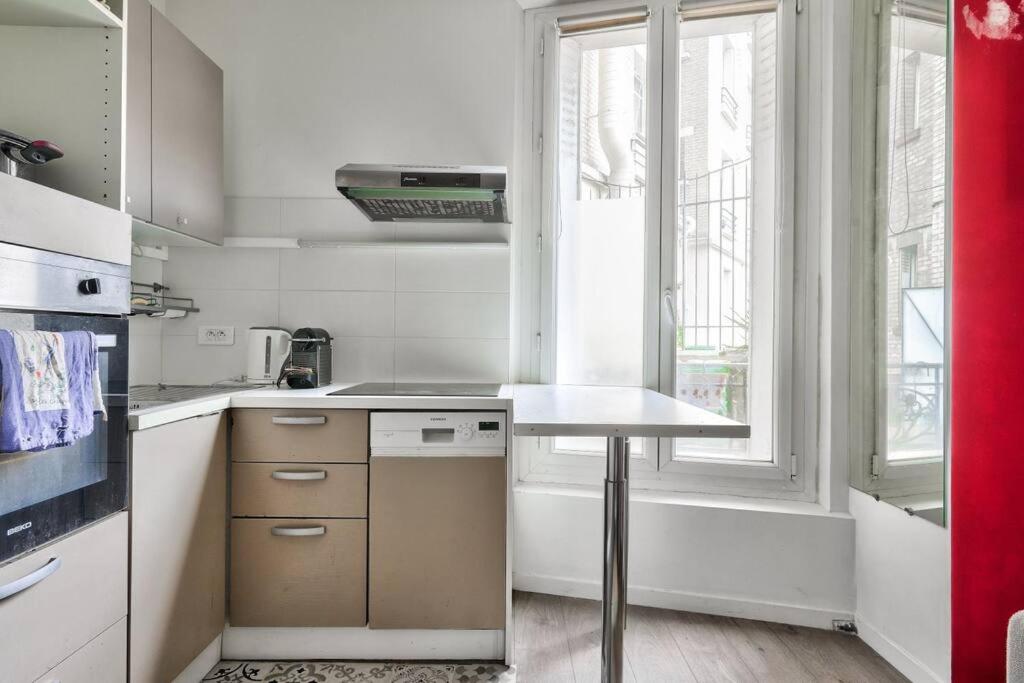 a white kitchen with a table and a window at Superbe T2 à proximité du parc Georges Brassens in Paris