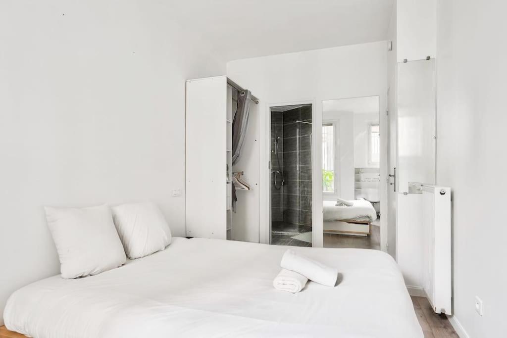 a white bedroom with a bed and a mirror at Superbe T2 à proximité du parc Georges Brassens in Paris