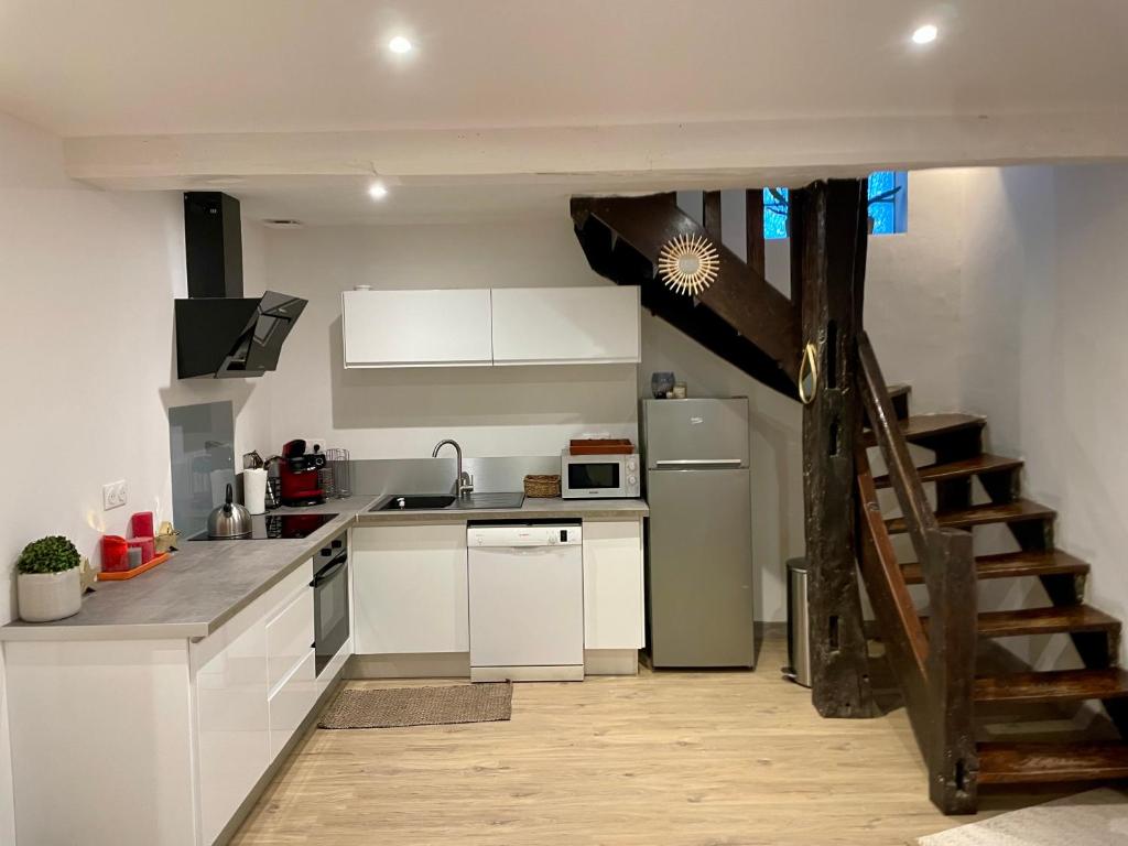 una cocina con armarios blancos y una escalera en una habitación en Maison au coeur de la Dombes, en Le Plantay