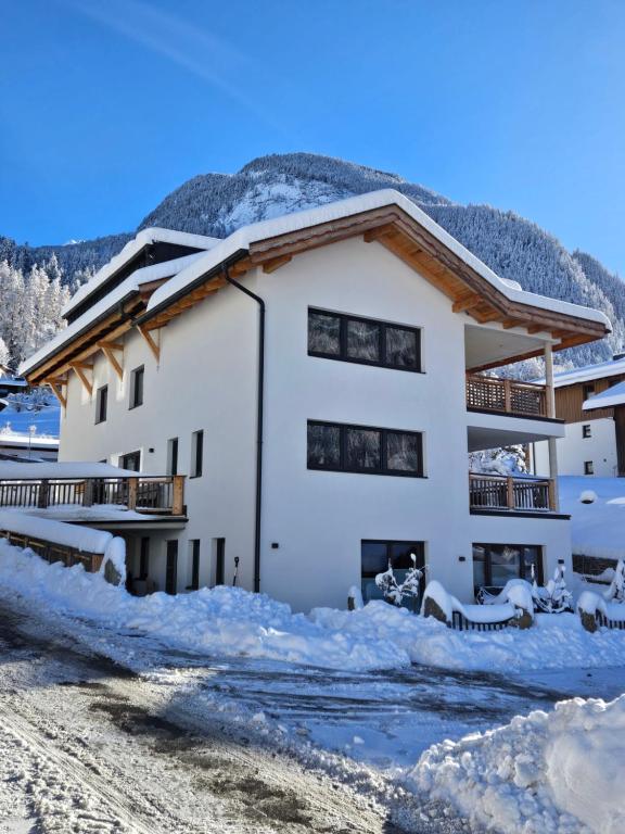 uma casa na neve com uma montanha ao fundo em Appartements Wolfgang Auderer em Jerzens