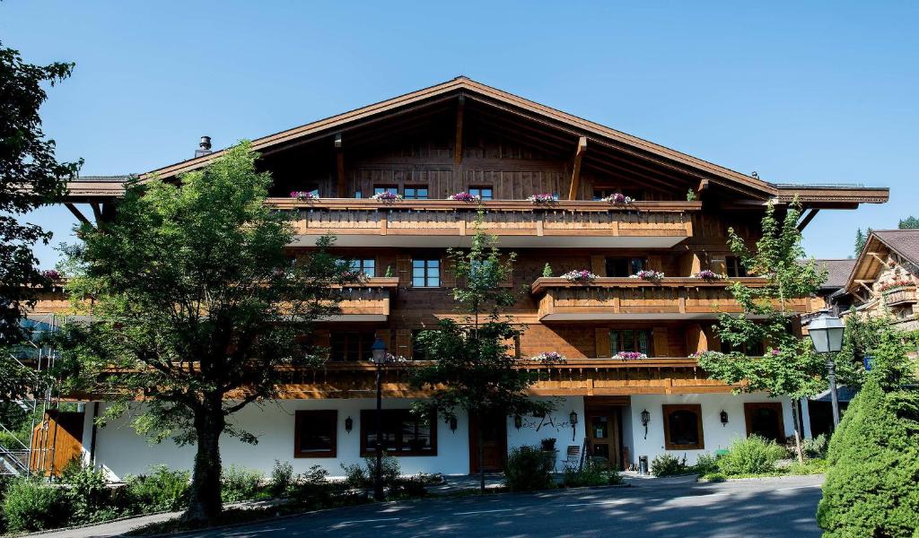 un grand bâtiment avec des personnes assises sur les balcons dans l'établissement Hotel des Alpes Superieur, à Gstaad