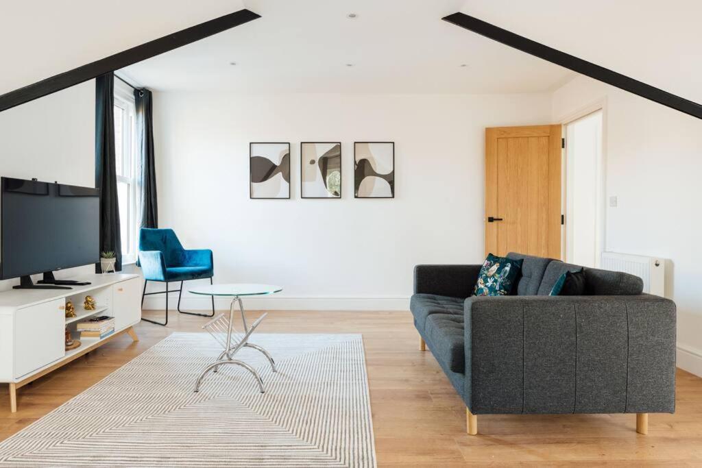 ein Wohnzimmer mit einem Sofa und einem TV in der Unterkunft Spacious & Modern Two Bedroom Apartment in Catford, London in Catford
