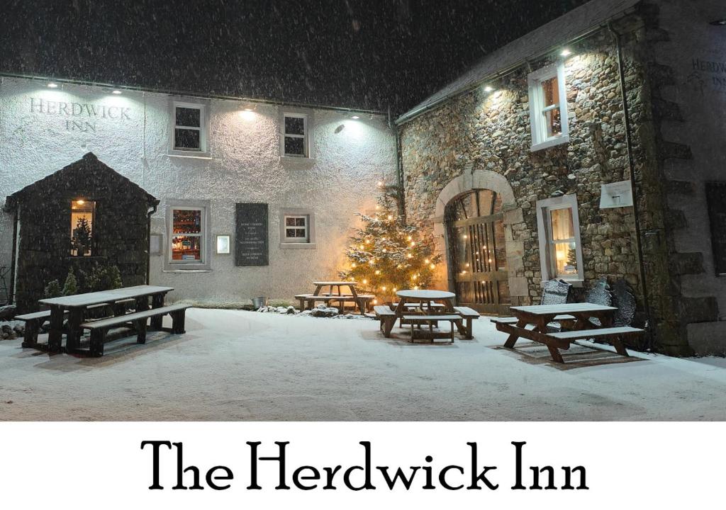 eine Gruppe Picknicktische im Schnee vor einem Gebäude in der Unterkunft The Herdwick Inn in Penruddock
