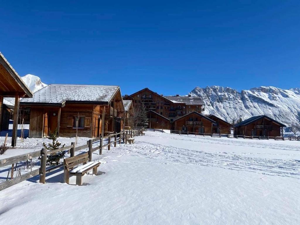 a snow covered field with a group of wooden buildings at Chalet de 3 chambres a Le Devoluy a 200 m des pistes avec piscine partagee sauna et balcon in Le Dévoluy