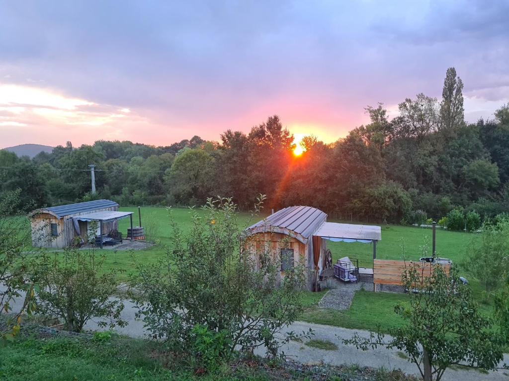 a group of huts in a field at sunset at Les Milles Bottes et ses Roulottes in Encausse-les-Thermes
