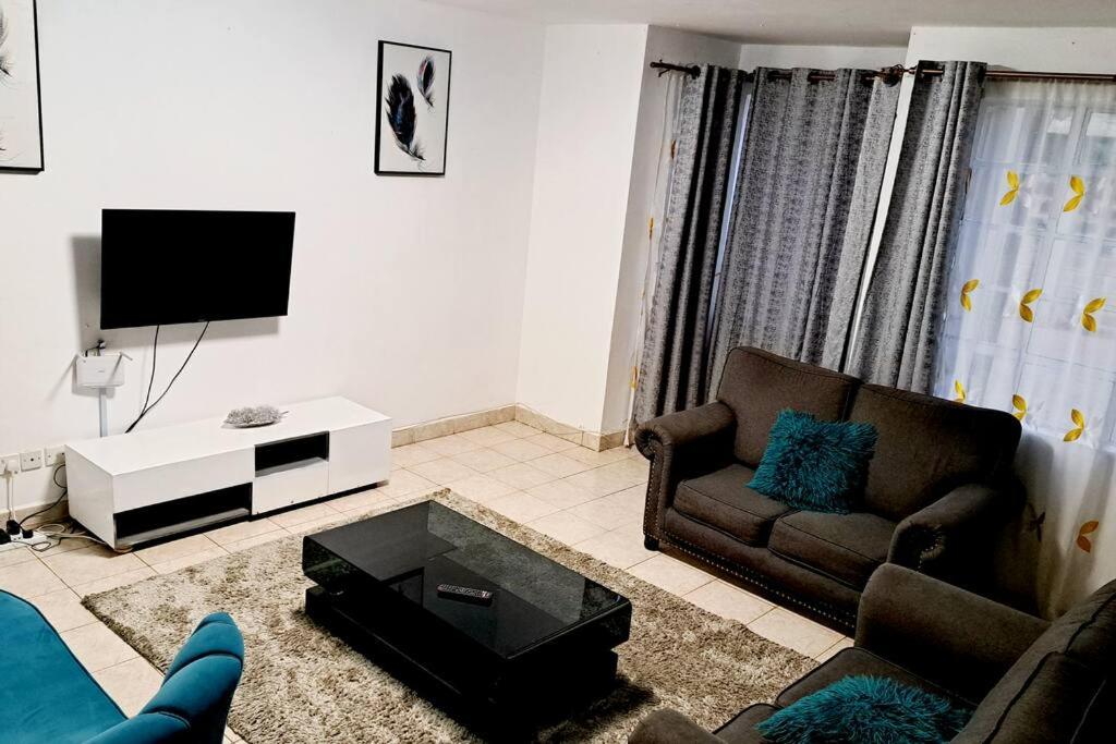 a living room with a couch and a tv at The Carina Homes in Kisumu