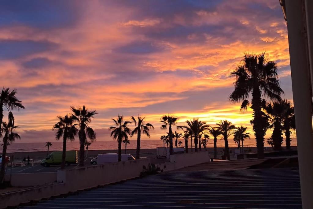 - un coucher de soleil sur une plage avec des palmiers et l'océan dans l'établissement Barcarès village - plage - mer - 4/9p+cour 3 étoil, au Barcarès